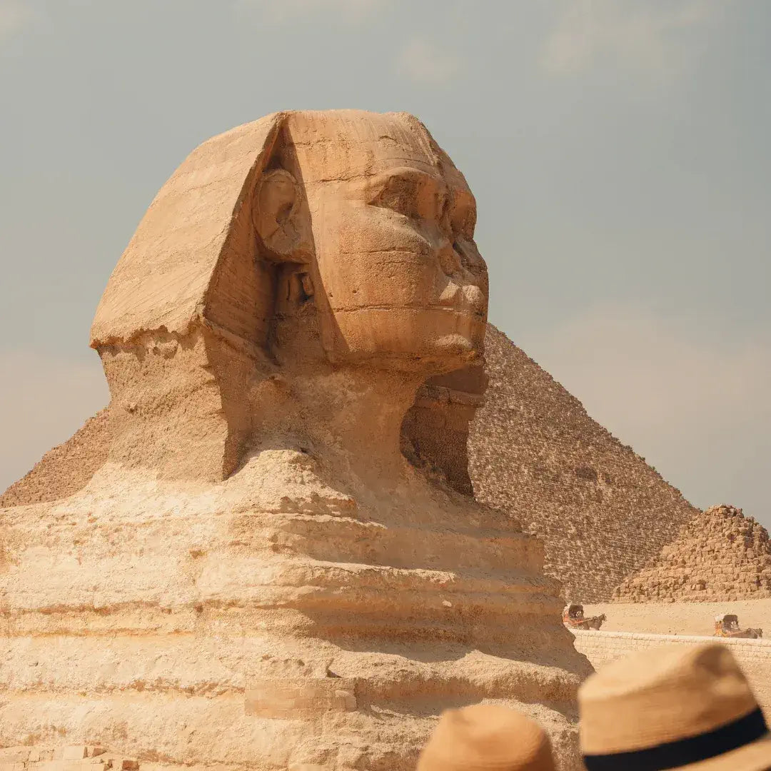 Sphinx and pyramid with tourists wearing hats in the foreground, Egypt - Stamps Tours